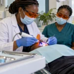 Dentist using an LED curing light and orange protective eyewear during restorative treatment