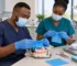 African dental team prepares rubber dam isolation supplies beside a training model.